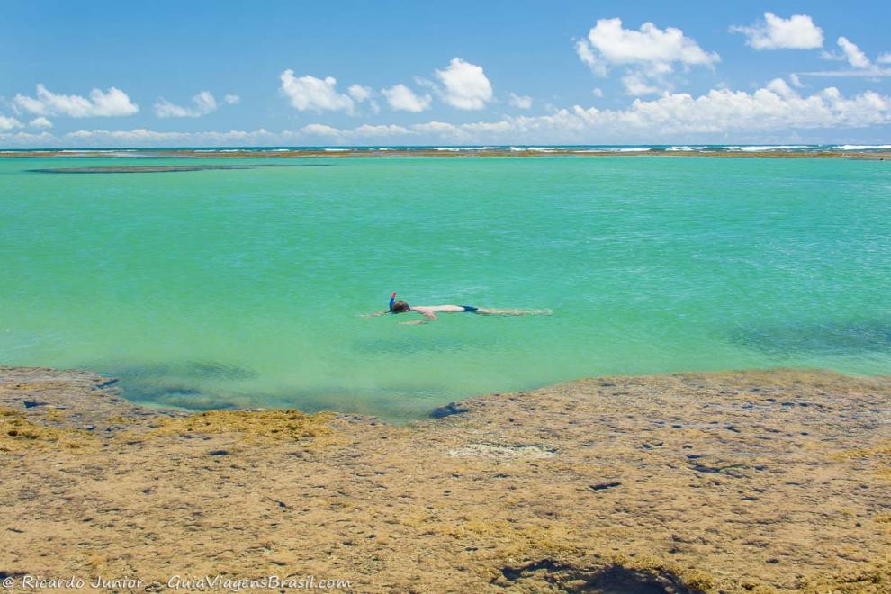 Imagem de um menino nadando com snorkel na piscina natural da Praia Taipu de Fora.